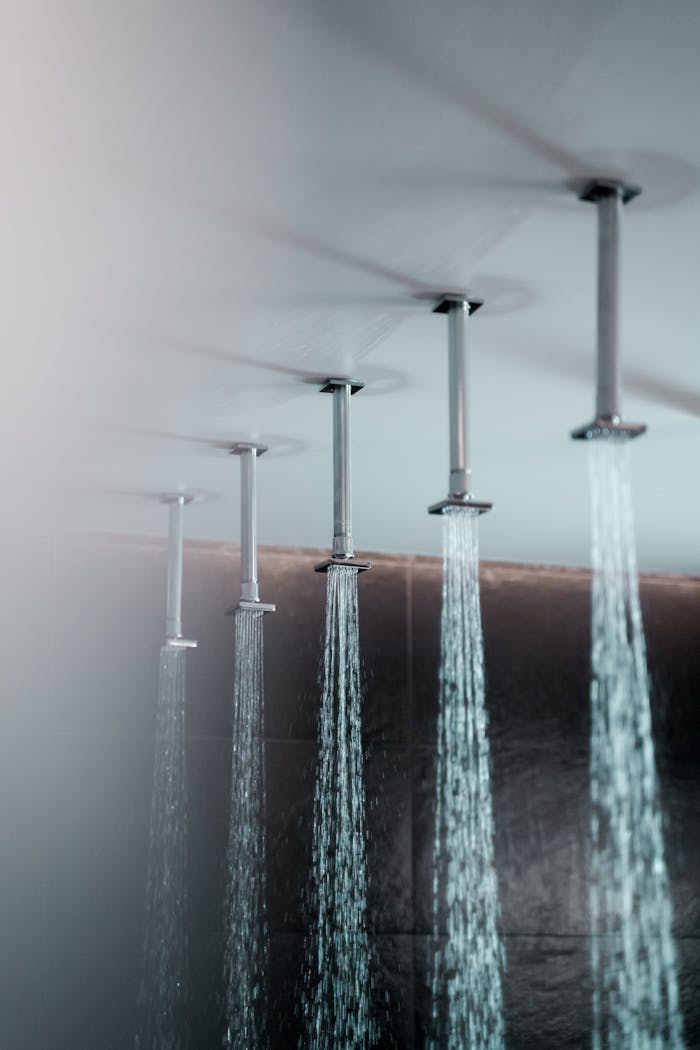 Ceiling-mounted rain showers with water streaming, creating a luxurious bathroom experience.